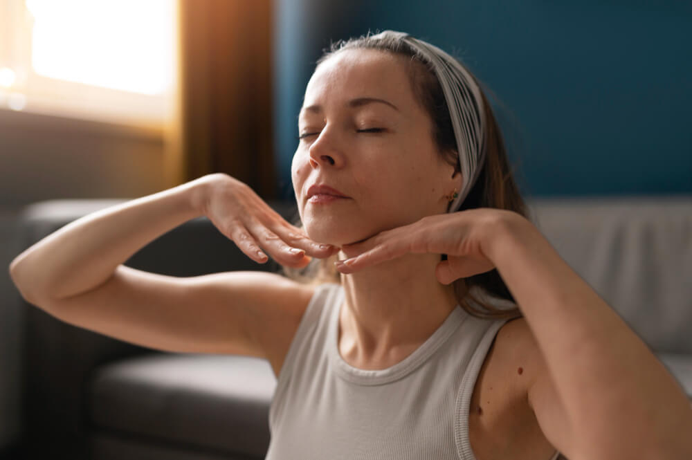 woman doing face yoga for her neck pain