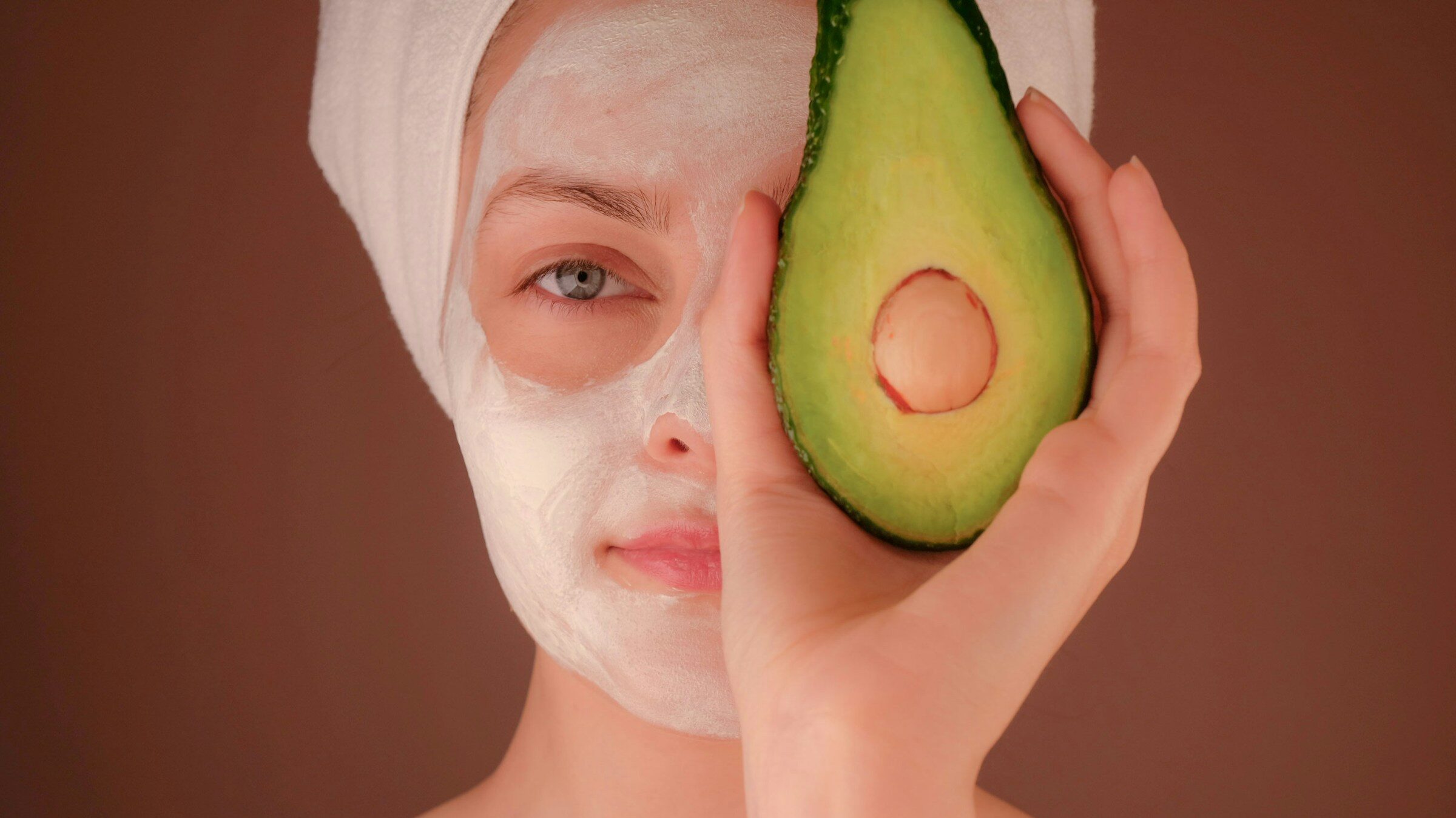 woman with an avocado at hand supporting face yoga